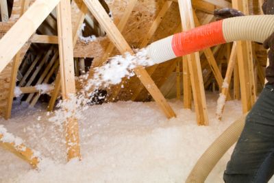 Tech Spraying Blown Fiberglass Insulation between Attic Trusses