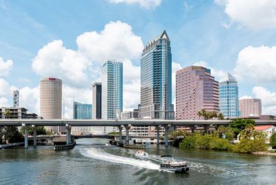 A river with boats in it and a bridge with tall buildings in the background