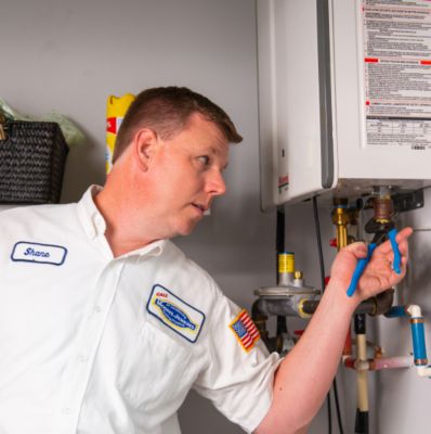 Technician fixing a tankless water heater with pliers
