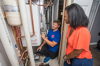 Coolray plumber working on tankless water heater smiling