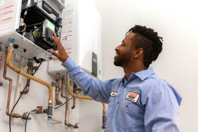 plumbing technician checking a tankless water heater in home