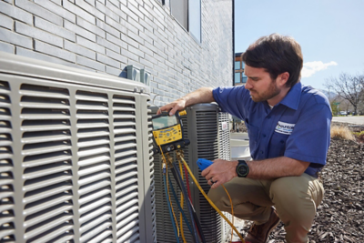 Tech outside repairing heat pump