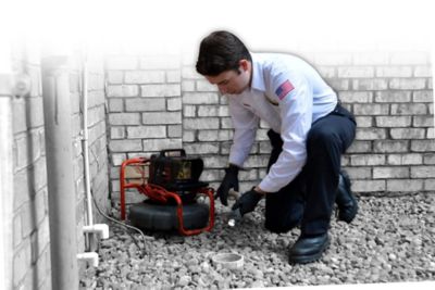 Technician setting up camera to look inside a drain