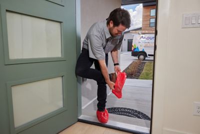 Tech putting on slippers at the front door