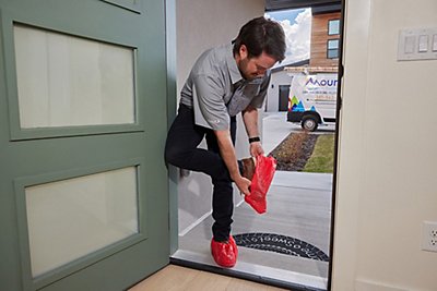 Tech putting on slippers at the front door