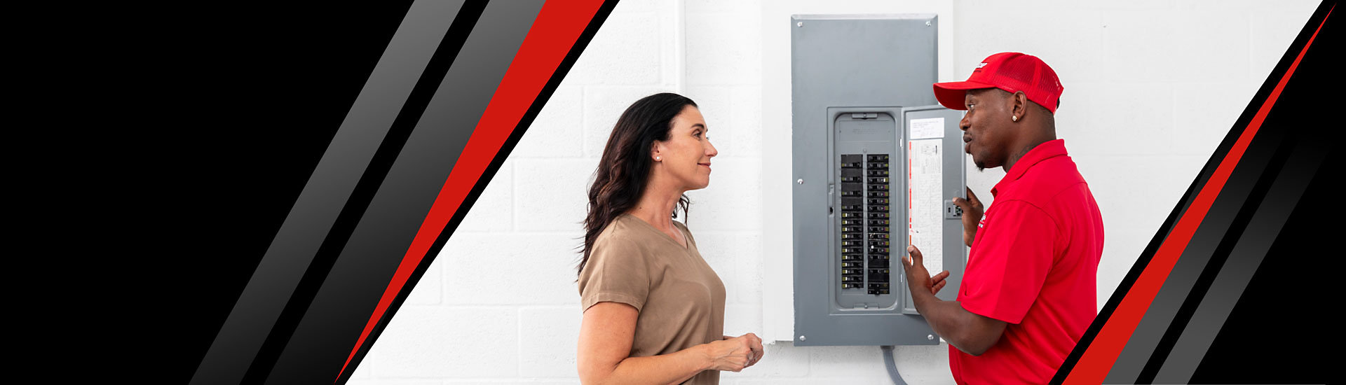 A Red Cap technician and a customer talking next to an electrical panel