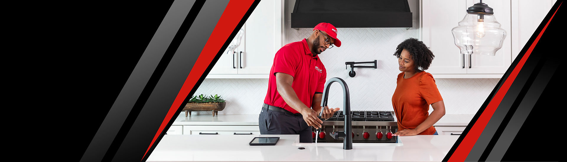 A Red Cap technician and a satisfied customer looking at a working faucet in a kitchen