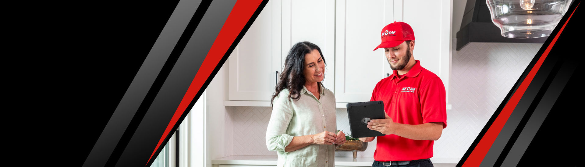 A happy customer and a Red Cap technician looking at a tablet in a kitchen