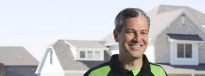 Technician smiling in front of a Cincinnati home - Thomas & Galbraith Heating, Cooling, & Plumbing