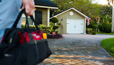 AC installation technician with tool bag arriving at a Jacksonville, FL home
