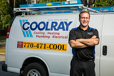 Coolray HVAC technician smiling in front of van at a home in Suwanee, GA