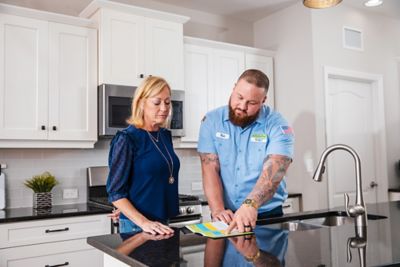 Technician and customer talking by the sink