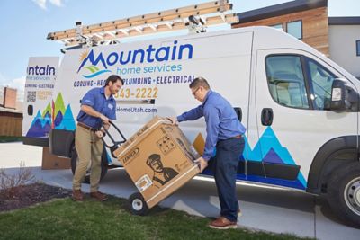 Two techs rolling new HVAC equipment to the house