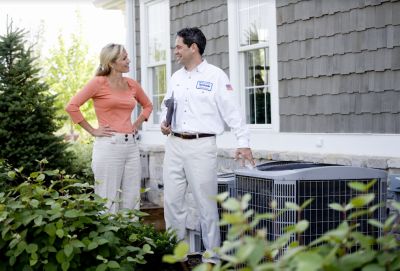 Tecnician with clipboard and customer next to AC unit