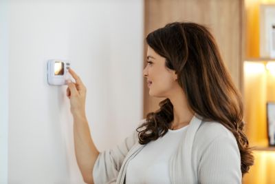 A happy woman is turning heat on in her apartment.