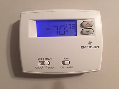 White thermostat on wall set to 70 degrees