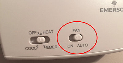 Close up of fan on and auto button on white thermostat