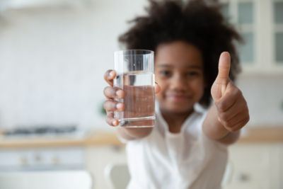 girl enjoying a glass of water at home