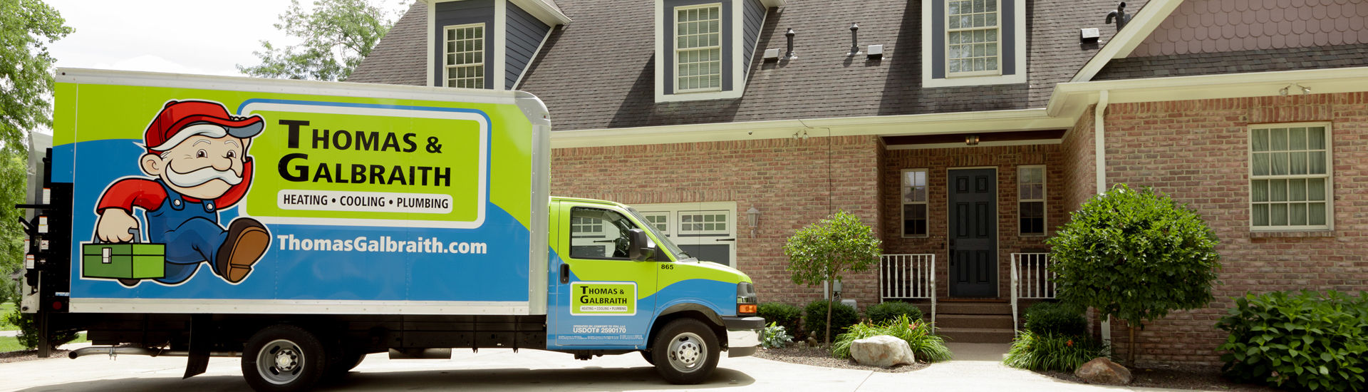 A man standing next to a Thomas & Galbraith Heating, Cooling & Plumbing van in front of a house.