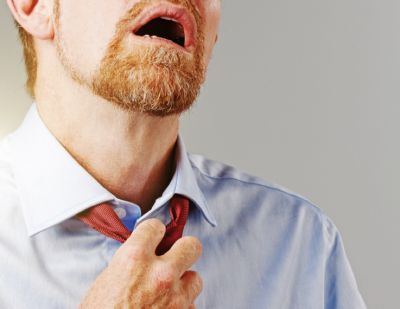 An upset man pulling on his tie.