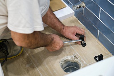 plumber installer installing toilet drain flange in a house 