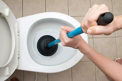 ToiletA person using a plunger to plunge the toilet