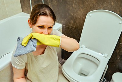 Unpleasant odors and aversion to dirt while cleaning. A woman cleans the home bathroom with a sense of disgust at the toilet bowl