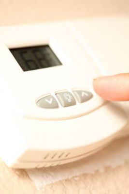 Person adjusting temperature on thermostat