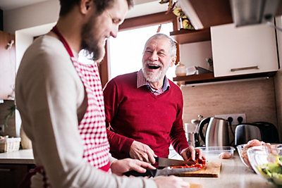 Two men preparing food in kitchen while smiling