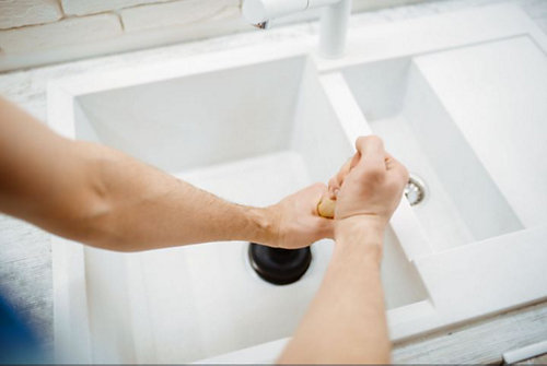 A person holding a plunger in a sink