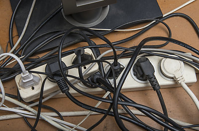 Plugs filling every socket of surge protectors with tangled wires