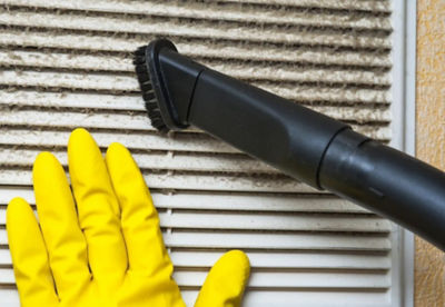 A vacuum cleaner removing dust from an air vent.