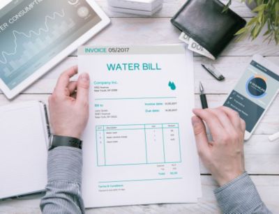 Man holding water bill sitting on desk