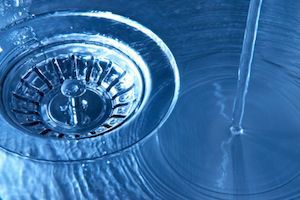 Water pouring into stainless steel sink toward drain