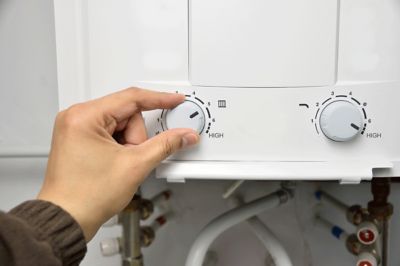 Hand adjusting a water heater dial