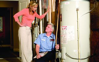 Plumber talking to homeowner while inspecting water heater