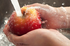 Water running over apple in hands