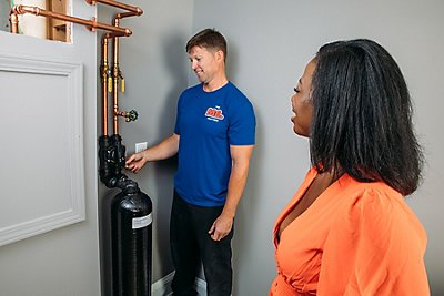 Plumber showing a customer a new water softener installed in their Atlanta area home