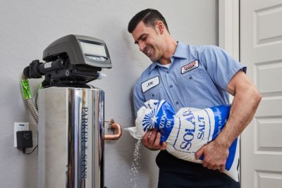 Technician putting salt into a water softener 