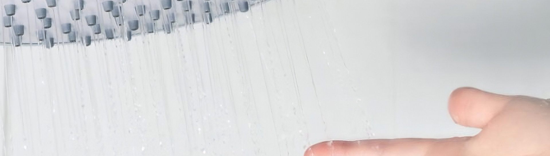 A person's hand under a shower head