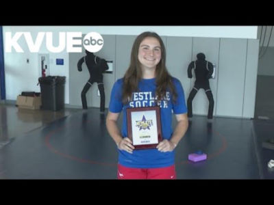 Westlake Soccer’s Kate Grannis standing in a gym holding a plaque.