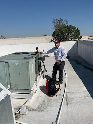 A man fixing a rooftop AC unit.