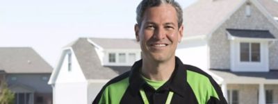 Technician smiling in front of an Indianapolis home - Williams Comfort Air Heating, Cooling, Plumbing & More