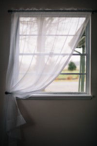 Small window with sheer curtain pulled aside