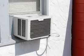 A portable air conditioner unit inside of a window.