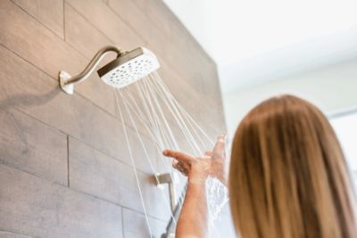 Woman checking the water temperature of a shower