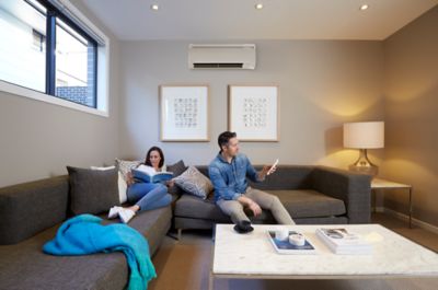 woman and man sitting on sofa, looking at phone and book