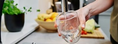 a hand pouring water into a glass