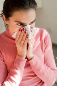 Woman sneezing into tissue