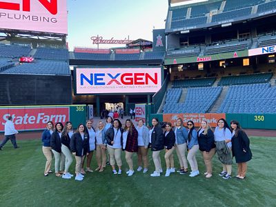 Woment of NexGen at a baseball field in front of NexGen display